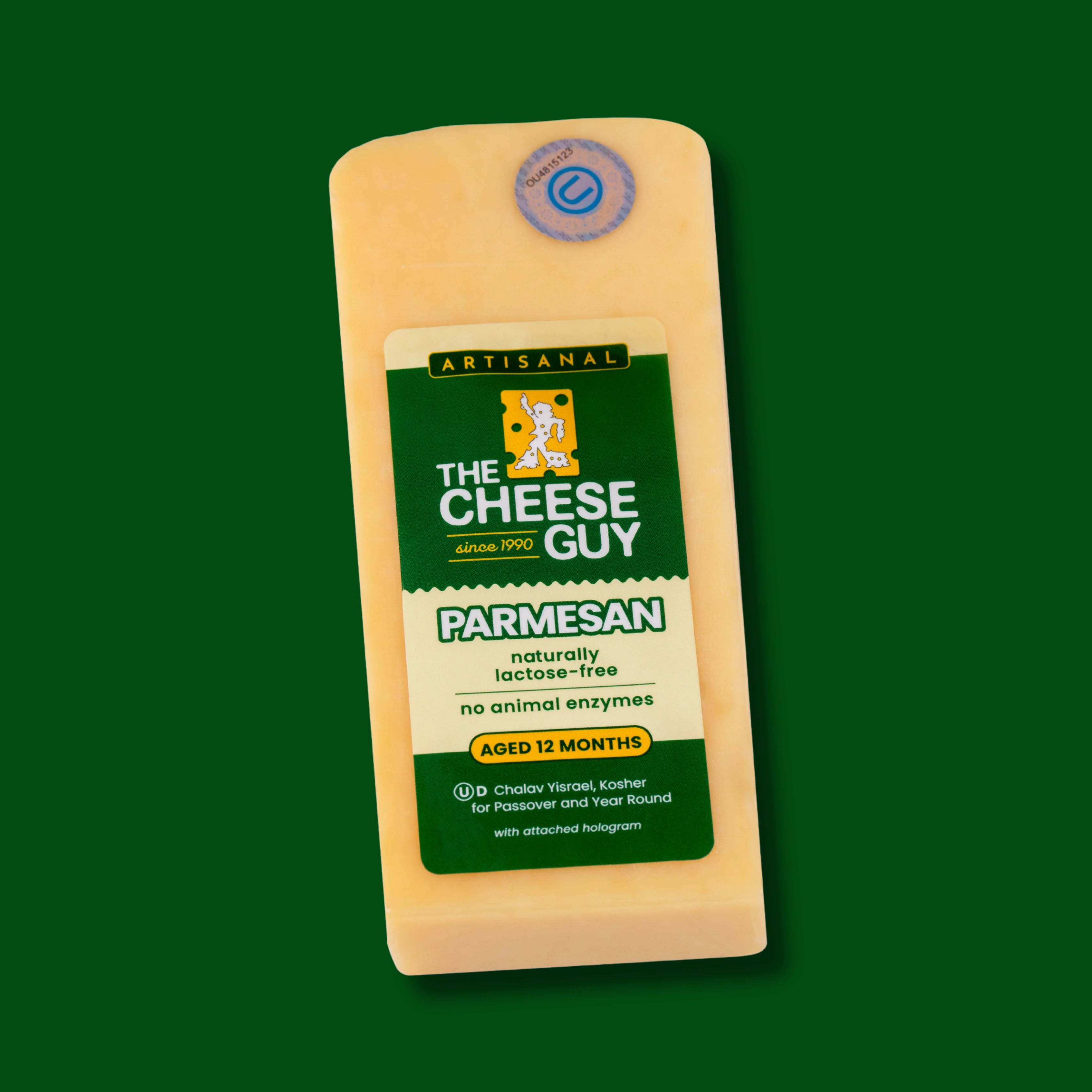 A block of The Cheese Guy Artisanal Parmesan cheese, naturally lactose-free, with no animal enzymes, aged 12 months, featuring a green label with the product name in bold letters and the company logo against a dark green background.