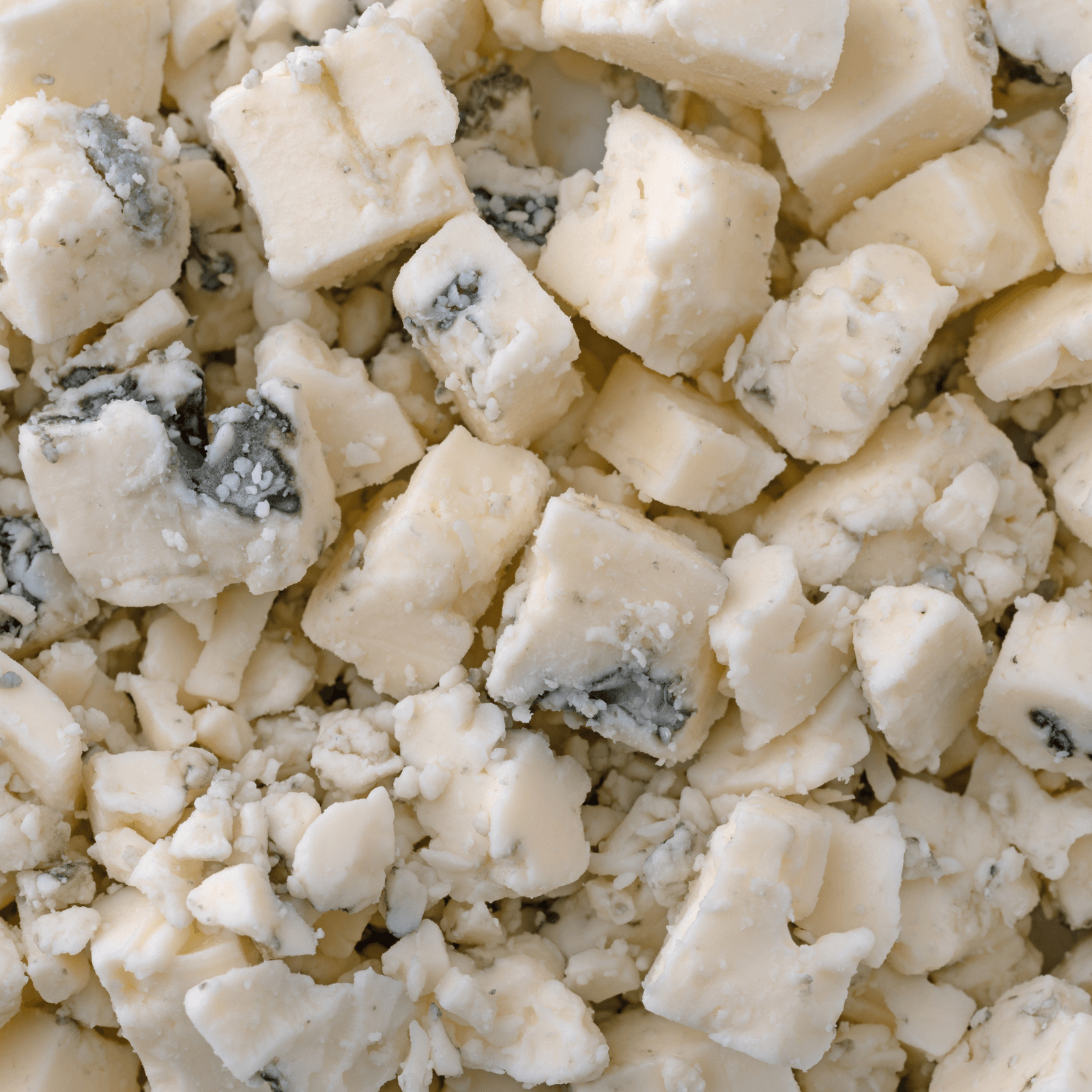 Close-up of crumbled blue cheese, displaying its white base with distinct blue veins, broken into irregular pieces.